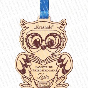 May include: A wooden owl figurine with large glasses and a book in its hands. The owl is holding a sign that says "Pasowanie Przedszkolaka Losia Świdwin 20.10.2022".
