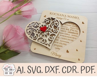 May include: A wooden heart-shaped card with a cutout design and a small red heart in the center. The card has the text "KOCHANA MAMO, dziękuję za..." and a list of words in Polish, including "troskę", "domowe obiady", "naukę życia", "ciepła", "wychowanie", and "przyjaźń". The card is signed "Maciej".
