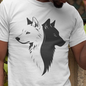 May include: White t-shirt featuring a black and white wolf design. The graphic shows two wolf profiles, one in white and the other in black, facing each other. The person in the image is wearing a brown hat and light blue jeans.