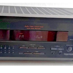 Può includere: Ricevitore stereo FM Sony nero con display digitale che mostra "FM 90.8". Il ricevitore ha vari pulsanti e manopole per il controllo audio, tra cui un'ampia manopola del volume. L'unità è progettata per sistemi audio domestici.