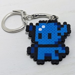 May include: A blue pixelated robot keychain with a silver metal ring and spring clasp.