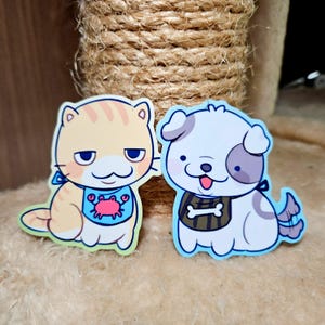 May include: Two cartoon stickers featuring a cat and a dog. The cat is orange with a blue bib and a crab design. The dog is white with gray spots and a bone-shaped bib. Both have cute expressions.