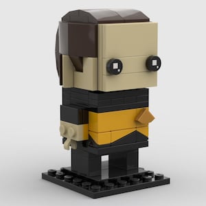 May include: A Lego-style figure of a Star Trek character. The figure has a tan face, brown hair, and black eyes. The uniform is black and gold. The figure is standing on a black base.