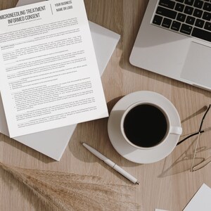 May include: A white sheet of paper with the title "Microneedling Treatment Informed Consent" and a section for a business name or logo. The paper is on a wooden table with a cup of coffee, a laptop, a pen, and a pair of glasses.