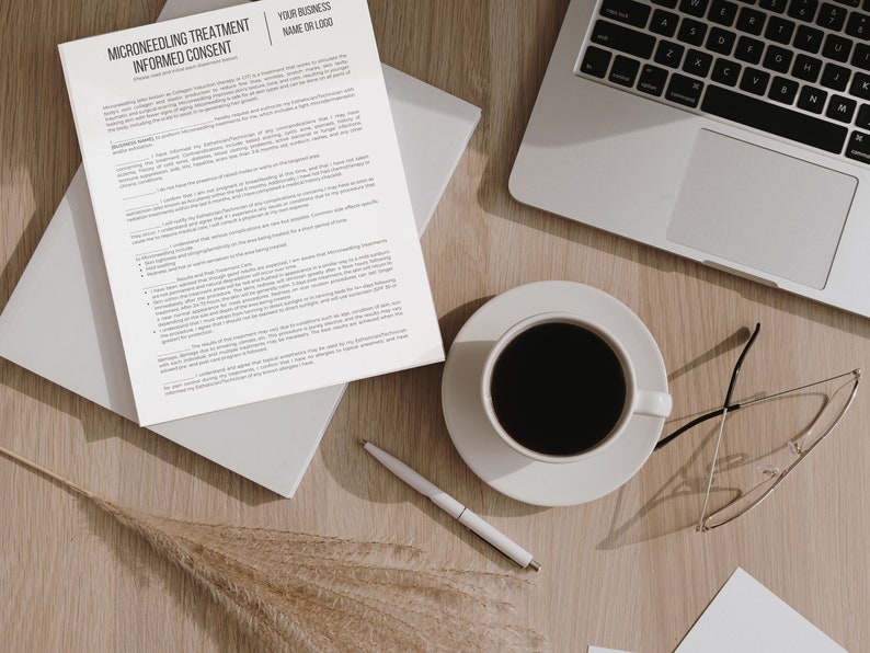 May include: A white sheet of paper with the title "Microneedling Treatment Informed Consent" and a section for a business name or logo. The paper is on a wooden table with a cup of coffee, a laptop, a pen, and a pair of glasses.
