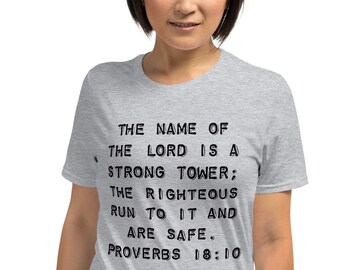 May include: A heather grey t-shirt with black text that reads "THE NAME OF THE LORD IS A STRONG TOWER; THE RIGHTEOUS RUN TO IT AND ARE SAFE. PROVERBS 18:10"