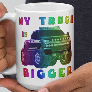 May include: White coffee mug with a rainbow colored graphic of a pickup truck and the text "My Truck Is Bigger".