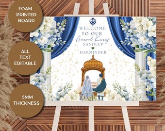 May include: A welcome sign for an Anand Karaj ceremony, featuring a blue and white floral design with the text "WELCOME TO OUR Anand Karaj SANDEEP HARMINDER". The sign is displayed on a wooden easel.