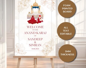 May include: A wedding welcome sign on an easel. The sign features a gold and red illustration of a ceremony scene, with the text "Welcome to the Anand Karaj of Sandeep & Simran" and the date 10.06.2024. The sign is a foam printed board.