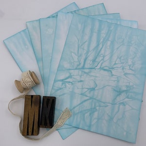 Papeles teñidos con efecto tie-dye de color aguamarina para revistas basura, fabricación de tarjetas y otras manualidades con papel