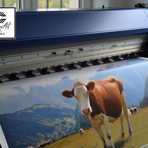May include: A large-format industrial printer outputting a high-resolution print of a brown and white cow standing in a grassy mountain meadow. The printer features a dark blue casing and a logo reading Canvas Art Store in the upper left corner.