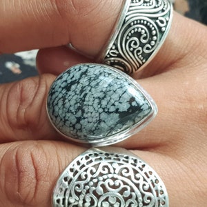 Peut inclure: Trois bagues en argent avec des motifs complexes. La bague du milieu présente une pierre mouchetée noire et blanche.