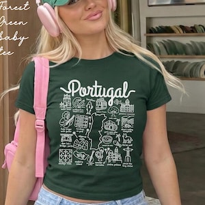 May include: A forest green short-sleeve t-shirt featuring a white graphic print of a map of Portugal surrounded by various cultural icons and the text "Portugal". The design includes illustrations of a rooster, a guitar, and landmarks.