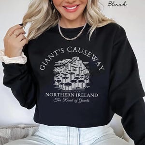 May include: Black cropped sweatshirt with a graphic of the Giant's Causeway in Northern Ireland. The text "Giant's Causeway" is written in a circular arc above the graphic, and the text "Northern Ireland" and "The Road of Giants" are written below the graphic.