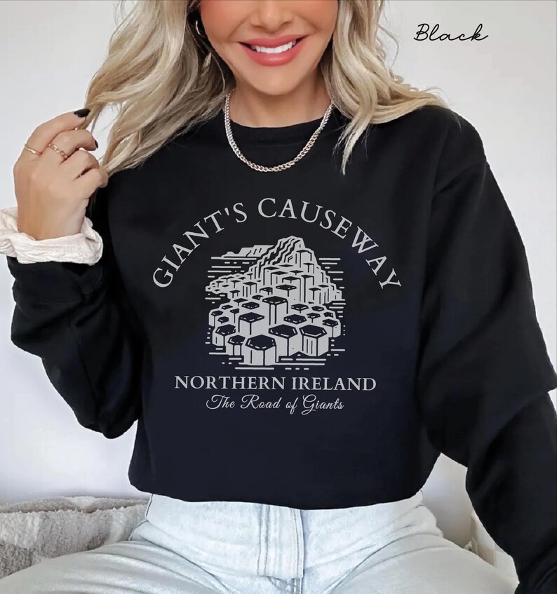 May include: Black cropped sweatshirt with a graphic of the Giant's Causeway in Northern Ireland. The text "Giant's Causeway" is written in a circular arc above the graphic, and the text "Northern Ireland" and "The Road of Giants" are written below the graphic.