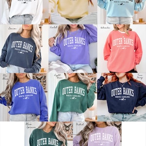 May include: A collection of crewneck sweatshirts in various colors, each displaying the text "OUTER BANKS NORTH CAROLINA" in a bold, arched font. The sweatshirts are in shades like white, yellow, blue, green, and pink, with a small horse graphic.