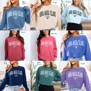 May include: A collection of long-sleeved sweatshirts in various colors, each displaying the text "ANNA MARIA ISLAND FLORIDA" in a white, arched font. The sweatshirts are in shades like blue, ivory, crimson, and violet.