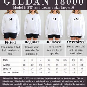 Pode incluir: Camisola Gildan 18000 branca com guia de tamanhos. A modelo tem 173 cm e veste tamanho grande. A tabela de tamanhos mostra as medidas de largura, comprimento e comprimento da manga. A camisola &eacute; 50% algod&atilde;o e 50% poli&eacute;ster.