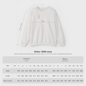 Pode incluir: Camisola branca Gildan 18000 com tabela de tamanhos. A tabela mostra medidas em polegadas e cent&iacute;metros para largura, comprimento e comprimento da manga, variando de XS a 5XL. O texto "Gildan 18000 sizes" tamb&eacute;m &eacute; vis&iacute;vel.