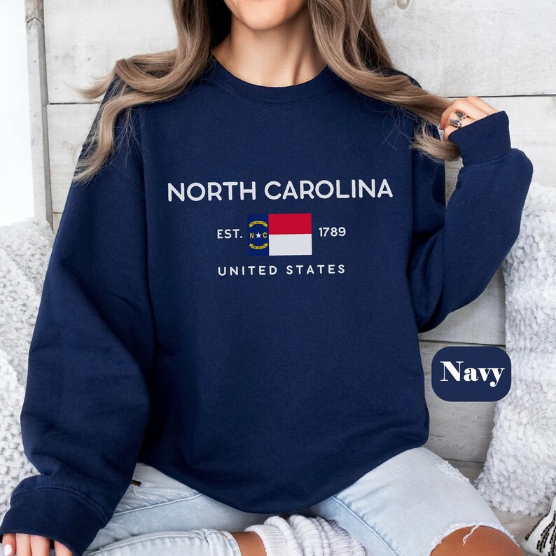 May include: Navy blue sweatshirt with white text that reads "NORTH CAROLINA EST. 1789 UNITED STATES" and a small image of the North Carolina state flag. The word "Navy" is written in white on a blue oval.