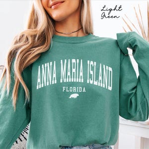 May include: Light green sweatshirt with the text "ANNA MARIA ISLAND FLORIDA" in white block letters. A small white illustration of a sea creature is below the word "FLORIDA". The words "Light Green" are written in cursive in the upper right corner.