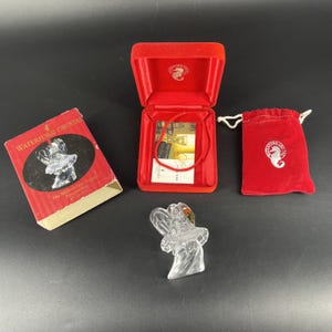 Op de afbeelding: Een Waterford Crystal engelbeeldje, met de originele doos en rode fluwelen presentatiekoffer. Op de doos staat "Waterford Crystal" en "The Millennium Angels". Een rood fluwelen zakje is ook inbegrepen.
