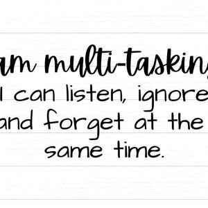 May include: A humorous quote about multitasking written in black cursive font on a white wood background. The quote reads: "I am multi-tasking... I can listen, ignore and forget at the same time."