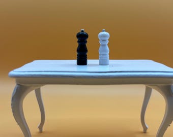 May include: A white table with two salt and pepper shakers, one black and one white, on top.