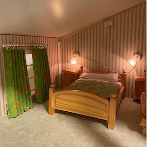 Puede incluir: Escena de dormitorio en miniatura con una cama de madera clara, mesitas de noche y cortinas verdes. La cama tiene una manta verde con estampado floral y una almohada blanca. Dos lámparas de pared iluminan la habitación, con papel pintado a rayas.