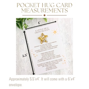May include: A white card with gold glitter accents and a gold star charm. The card measures 5.5 inches by 4 inches and reads "A Little Hug From Heaven". The card includes a poem about being with someone in spirit and a reminder that they are always there.