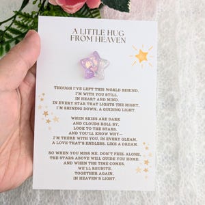 May include: A white card with a purple star-shaped resin charm attached. The card has gold stars and the text "A Little Hug From Heaven" and a poem about remembering a loved one.