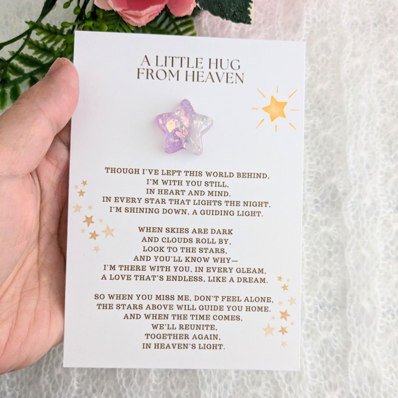 May include: A white card with a purple star-shaped resin charm attached. The card has gold stars and the text "A Little Hug From Heaven" and a poem about remembering a loved one.