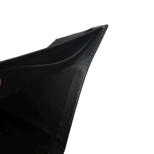 May include: A black leather wallet, open to reveal the interior. The wallet is made of a smooth, dark material with visible stitching along the edges. The interior appears to have multiple compartments for cards or cash.