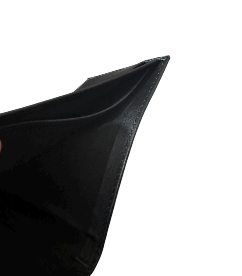 May include: A black leather wallet, open to reveal the interior. The wallet is made of a smooth, dark material with visible stitching along the edges. The interior appears to have multiple compartments for cards or cash.
