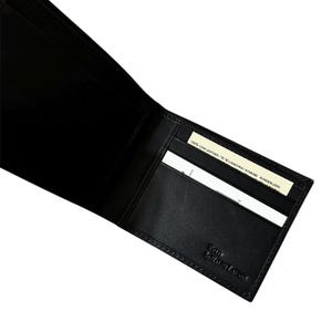 May include: Open black leather wallet with card slots. The wallet is embossed with "POLO by RALPH LAUREN" on the lower right corner. A small tag reads "100% COW LEATHER".