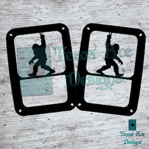May include: Two black metal frames with a silhouette of a Bigfoot hanging from a rope inside each frame. The frames are on a wood background.