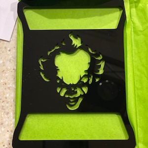 May include: Black acrylic wallet insert with a cutout of a scary clown face.