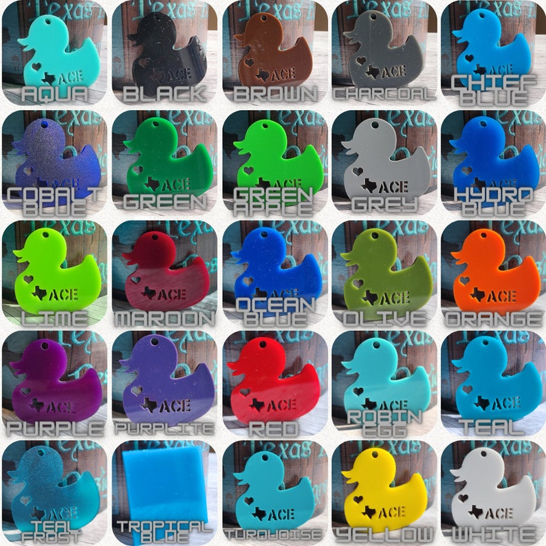May include: A collection of 25 rubber ducky keychains in various colors, including teal, turquoise, purple, red, orange, yellow, green, blue, black, brown, grey, white, and lime. Each ducky has a heart-shaped cutout with the word "ACE" inside.