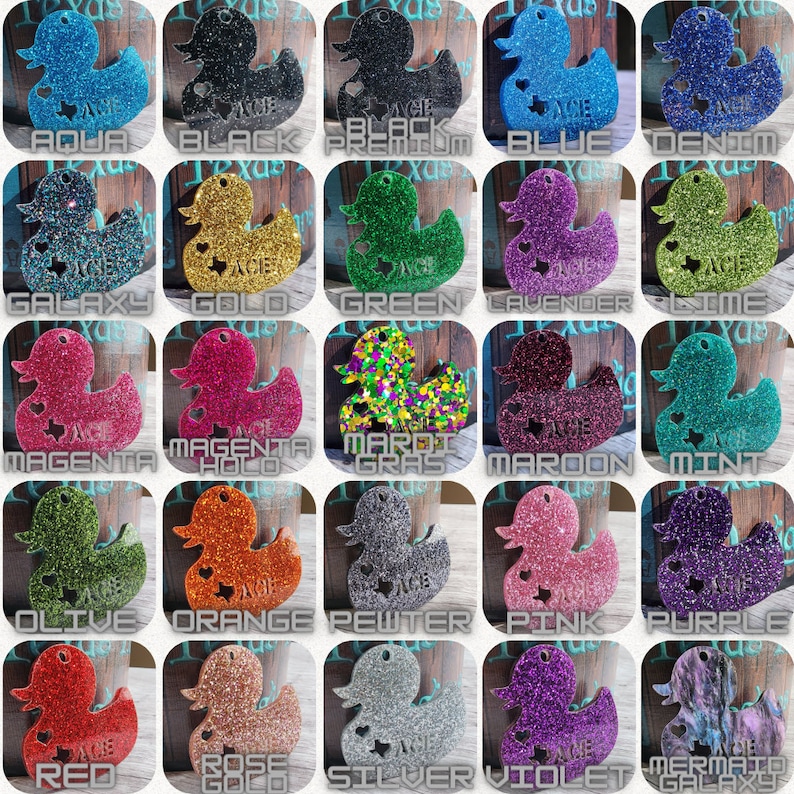 May include: A collection of 25 rubber duck keychains, each with a different glitter color and design. The keychains are arranged in a grid, with each row representing a different color. The colors include aqua, black, blue, denim, galaxy, gold, green, lavender, lime, magenta, magenta holo, mardi gras, maroon, mint, olive, orange, pewter, pink, purple, red, rose gold, silver, violet, and mermaid galaxy.