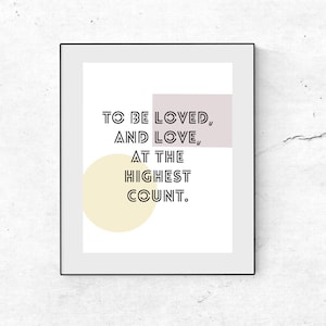 May include: A black framed print with a white background and a quote that reads "To be loved, and love, at the highest count." The quote is in black text with a light pink rectangle behind the first two lines and a yellow circle behind the last two lines.