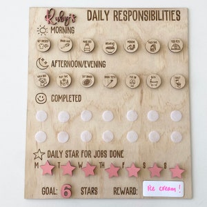 May include: Wooden daily responsibility chart with the name "Ruby's" at the top. The chart includes icons for morning, afternoon/evening tasks, and a section for completed tasks. Pink star stickers track jobs done, with a goal of 6 stars and a reward of "ice cream!"