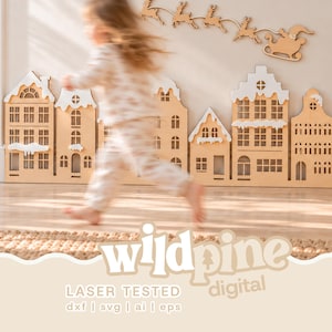 May include: A laser-cut wooden Christmas village display featuring multiple house facades with white painted roofs and a separate silhouette of Santa Claus in a sleigh pulled by reindeer, labeled with the text wildpine digital.