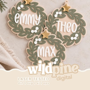 Könnte beinhalten: Drei kreisförmige Holzornamente mit einem salbeigrünen Kranzdesign, weißen Beeren und einem goldenen Stern an der Spitze. Jedes Ornament zeigt einen weißen Namen in Schreib- oder Blockschrift: Emmy, Theo und Max. Der Text wildpine digital ist sichtbar.