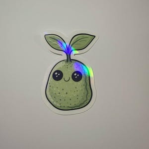May include: A holographic sticker featuring a cute, smiling pear-shaped sprout. The sprout has two green leaves and a light green body with small dots. The sticker has a white border and a holographic effect that reflects rainbow colors.