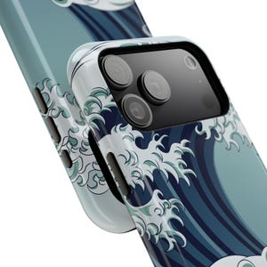 May include: A close-up of a smartphone case featuring a Japanese wave pattern in shades of blue and white. The case has a glossy finish and a protective design, with a camera module visible.