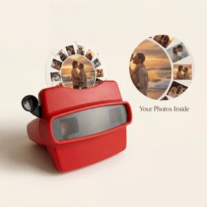 Puede incluir: Un juguete View-Master rojo con un carrete de fotos que muestra imágenes de una pareja. El carrete se inserta en el View-Master y el texto "Your Photos Inside" es visible a la derecha.