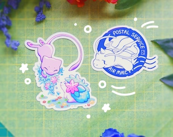 Puede incluir: Dos pegatinas con personajes de dibujos animados. Una pegatina muestra una criatura rosa con una cola larga y un diseño floral. La otra pegatina es un diseño azul y blanco con el texto "Postal Service Air Mail".
