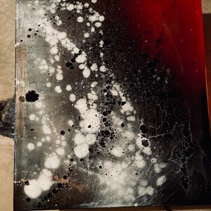 May include: Abstract art painting on canvas with black, white, and red paint splatters. The painting has a gradient effect with black and white on the left side and red on the right side.