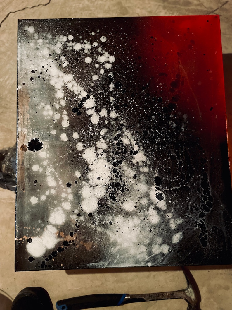 May include: Abstract art painting on canvas with black, white, and red paint splatters. The painting has a gradient effect with black and white on the left side and red on the right side.