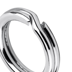 Op de afbeelding: Een zilverkleurige metalen sleutelhanger met een glad, afgerond oppervlak. De ring is ontworpen om duurzaam en veilig te zijn om sleutels of andere kleine voorwerpen aan te bevestigen.